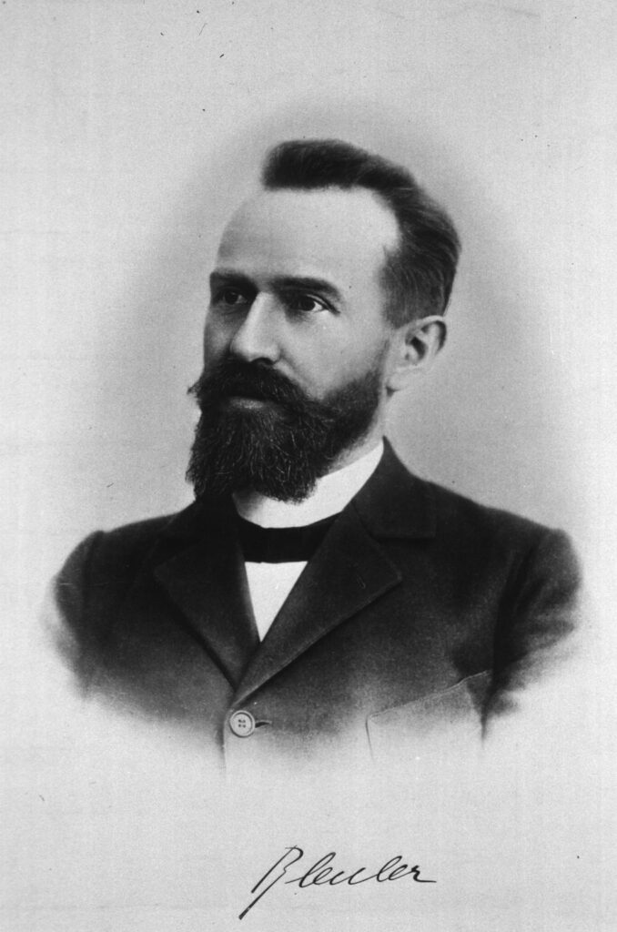 Es ist eine Autogrammkarte mit einem schwarz-weißen Foto von Eugen Bleuler. Es zeigt ihn als jungen Mann mit Vollbart, hochgeschlossenem weißen Hemd und Fliege. Er trägt einen Mantel. Trotz seines jungen Alters hat er Geheimratsecken, die dunklen Haare sind nach hinten gekämmt. Unter dem Foto steht seine handgeschriebene Unterschrift.