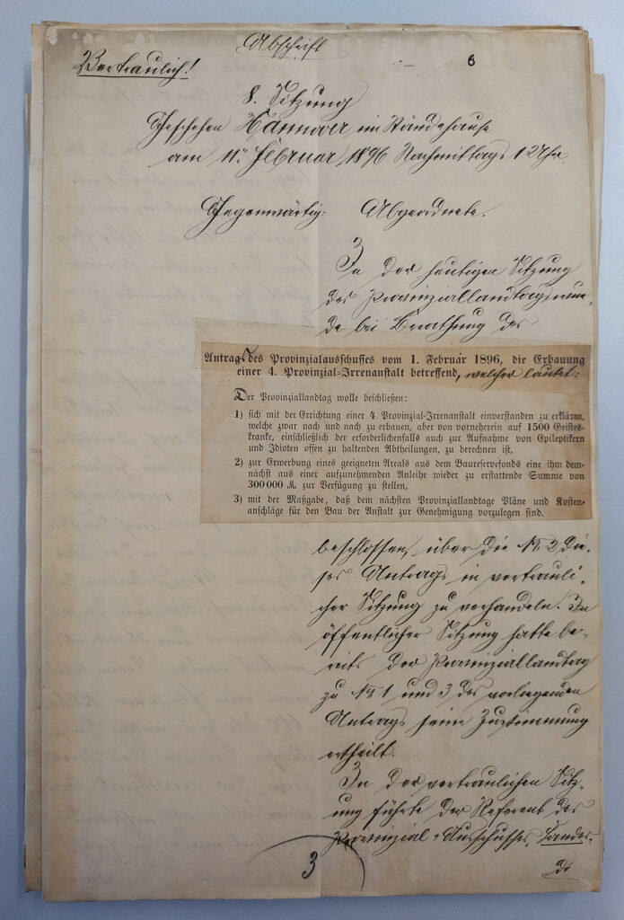 Es ist ein vergilbtes Papier. Der Text ist handschriftlich in sauberer Schreibschrift. Zu lesen ist, dass es sich um eine vertrauliche Abschrift handelt. In der Mitte des Papiers ist der Beschlussvorschlag über die Errichtung einer vierten Anstalt auf dem Gebiet der Provinz Hannover als Papierschnipsel aufgeklebt. Der Beschlussvorschlag ist in Frakturschrift gedruckt. Unter dem Beschlussvorschlag geht das Protokoll handschriftlich weiter.
