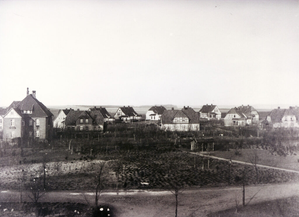 Es ist ein schwarz-weißes Foto. Es zeigt die »Wärtersiedlung« in einer Totale, es sind zwölf Fachwerkhäuser und ein Backsteinhaus, das Oberwärterhaus, zu sehen. Im Vordergrund ist ein Park mit neu angelegten Wegen und frisch angepflanzten Bäumen.