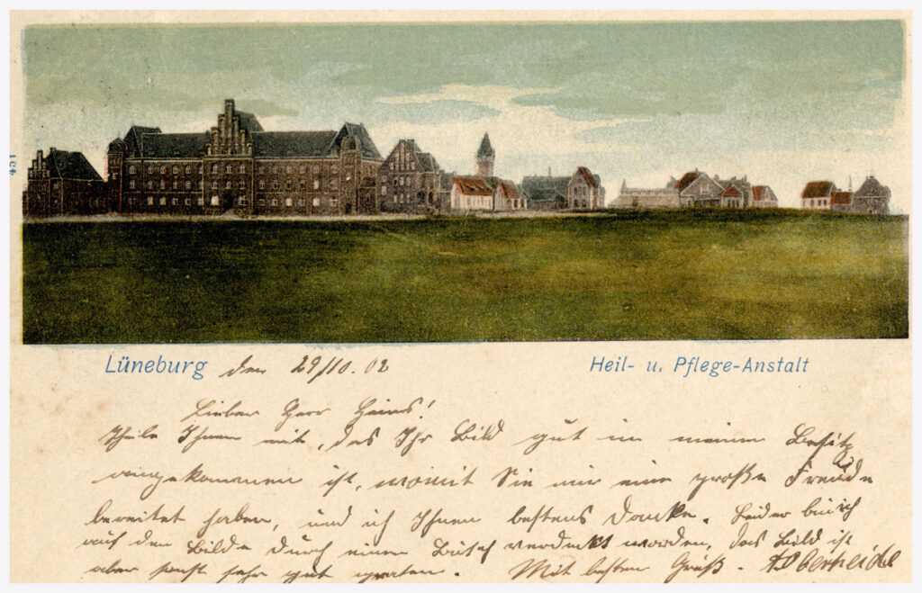 Es ist eine historische Postkarte im Querformat mit einer kolorierten Bleistiftzeichnung der Heil- und Pflegeanstalt Lüneburg. Die Zeichnung bildet die obere Hälfte der Postkarte. Auf der Zeichnung ist das Verwaltungsgebäude sowie ein Teil der »Wärtersiedlung« zu erkennen. Im Hintergrund ist der Wasserturm. Unter der Zeichnung steht in blau gedruckter Schrift: Lüneburg, Heil- u. Pflege-Anstalt. Auf der unteren Hälfte der Postkarte ist mit schwarzer Tinte eine Nachricht handgeschrieben. Der Verfasser bedankt sich für ein Bild, das in seinen Besitz gekommen ist. Die Nachricht ist unterzeichnet mit »A. Oberheide«.