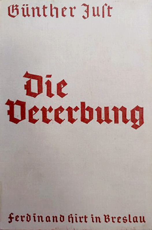 In der Vitrine ist die Originalausgabe des Buches. Das Buch ist geschlossen. Es ist in festem, hellbeigen Einband. Der Titel des Buches ist in dunkelroter Frakturschrift auf den Deckel gedruckt.