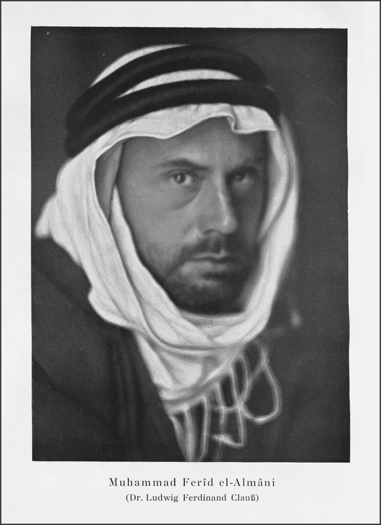 Es ist ein schwarz-weißes Fotoporträt eines mittelalten Ludwig Clauß. Er trägt eine Chutra (ein Tuch), die von den Agaal (zwei schwarzen Ringen) gehalten wird. Er trägt ein arabisches Gewand. Es hat einen nicht gepflegten Vollbart und schaut mit seinen tiefdunklen Augen direkt in die Kamera.