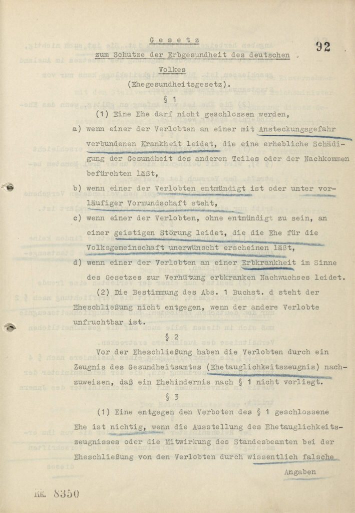 Es ist eine Seite aus dem »Gesetz zum Schutze der Erbgesundheit des Deutschen Volkes«. Das Papier ist leicht vergilbt. Der Text ist eng gedruckt. Im Gesetz sind handschriftliche Unterstreichungen mit blauem Bundstift. Die Passagen sind dadurch hervorgehoben.