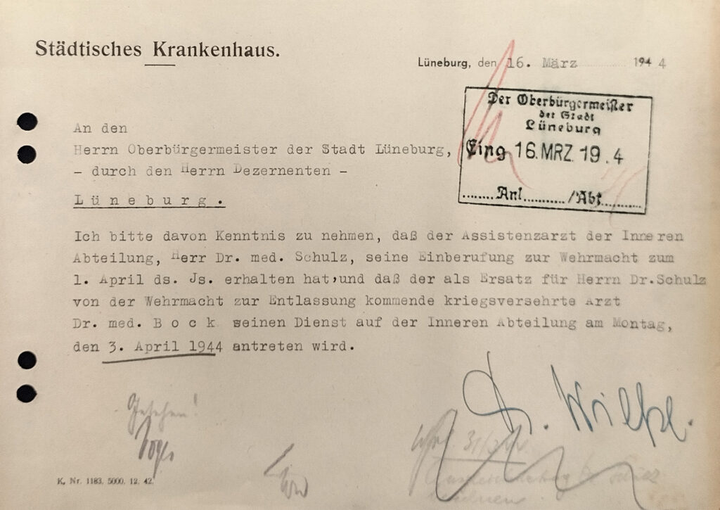 Es ist ein DIN A5-Papier im Querformat. Das Papier ist hellbraun und wurde mit einer Schreibmaschine getippt. Es wird mitgeteilt, dass der Arzt Helmut Bock als Vertretung von Günther Schulz, der zur Wehrmacht eingezogen wurde, seinen Dienst antritt. Es gibt einen Stempel vom Oberbürgermeister. Die Mittelung ist unterschrieben von Adolf Wilke.