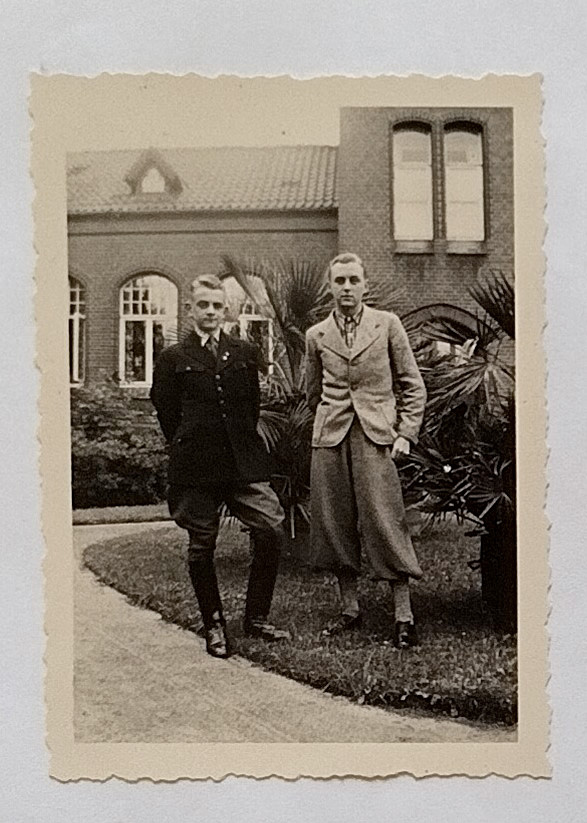 Es ist ein schwarz-weißes Foto der noch jung wirkenden Brüder Marx. Beide stehen auf einer Grünfläche mit Palmen vor einem Gebäude der Heil- und Pflegeanstalt Lüneburg. Es ist im Hintergrund zu erkennen. Gustav Marx trägt ein kariertes Hemd, eine Knickerbocker mit Strümpfen und ein Jackett in hellem Wollstoff. Sein Bruder steht links neben ihm. Er trägt eine Reiterkluft mit Stiefeln, ausgestellter Hose und dunklem Jackett. Beide stehen in lässiger Haltung. Sie blicken ernst.