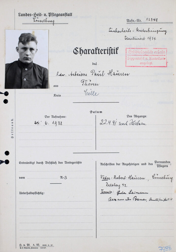 Es sind drei Seiten des Charakteristikbogens, zwar den Vorgaben entsprechend, jedoch in diesem Fall sehr spärlich handschriftlich ausgefüllt. Der Bogen ist ein Formular, in dem persönliche Informationen abgefragt werden. Das Feld, in dem der Einweisungsgrund darlegt sein muss, ist leer. Oben links auf der ersten Seite ist ein schwarz-weißes Passfoto von Paul Hausen aufgeklebt. Ein roter Stempel neben der Überschrift lautet: »Erbbiologisch erfasst«.
