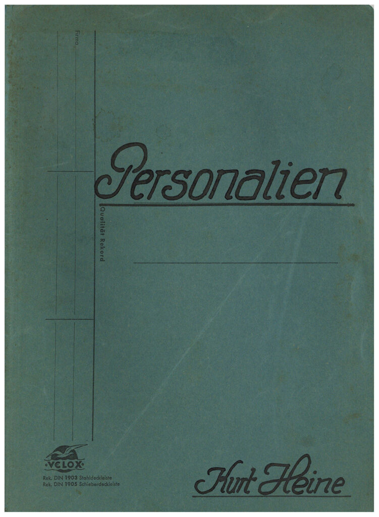 Es ist ein blauer Papphefter. Mittig auf dem Titel steht in schmuckvoller schwarzer Schrift »Personalien«. In der gleichen Schrift steht unten rechts »Kurt Heine«.