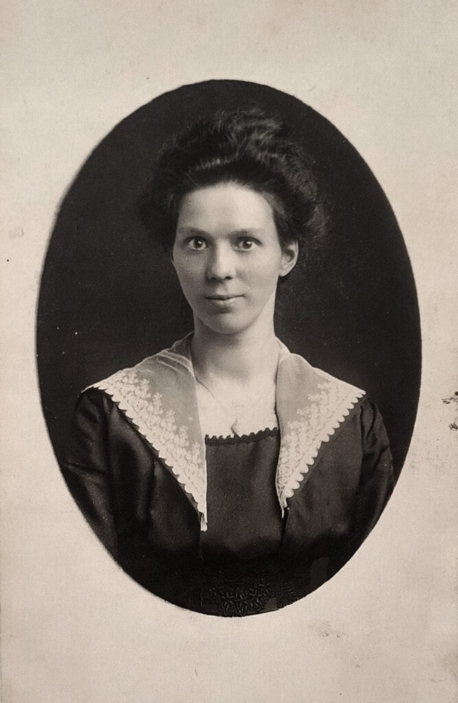 Es sind drei schwarz-weiße Bilder nebeneinander. Zwei rechteckige und in der Mitte ein ovales Porträtbild. Das linke Bild zeigt Therese Schubert in einem hellen opulenten Kleid mit hellem Hut. Sie steht sehr aufrecht und hat die rechte Hand hinter dem Rücken. Das mittlere ist ein Porträt. Therese Schubert trägt ein dunkles Oberteil mit einem hellen Überwurf. Ihre Haare sind locker nach hinten gesteckt. Sie blickt freundlich direkt in die Kamera. Das rechte Bild zeigt Therese Schubert in einem hellen opulenten Kleid mit hellem Hut. Sie steht an eine Säule gelehnt. Sie blickt freundlich direkt in die Kamera.