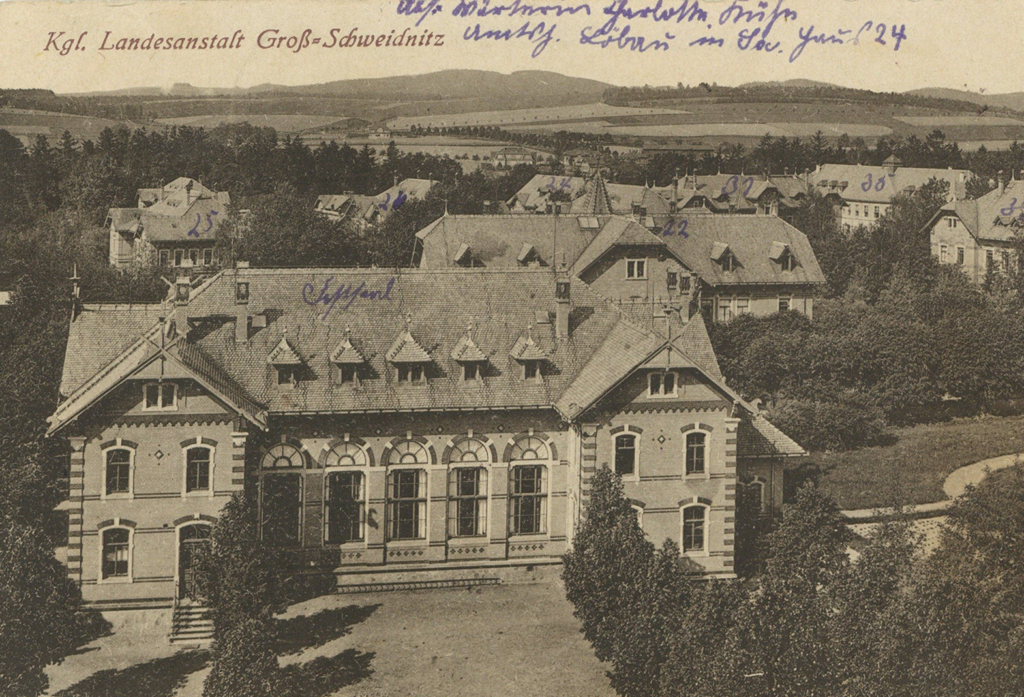 Es ist ein schwarz-weißes Bild. Zu sehen sind mehrere ähnlich aussehende villenartige Gebäude. Die Gebäude sind zweistöckig mit verzierten Backsteinmauern und hohen Sprossenfenstern. Handschriftlich ist oben auf die Karte mit blauem Stift eine Notiz aufgeschrieben. Die Gebäude sind außerdem handschriftlich nummeriert und beschriftet.