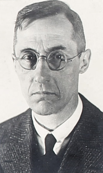 Es ist ein schwarz-weißes Porträtfoto von Edzard Stölting im mittleren Alter. Er trägt seine Haare gescheitelt und eine runde Nickelbrille. Er hat ein Jackett an mit einem weißen Hemd und einer Krawatte. Er blickt ernst mit heruntergezogenen Mundwinkeln in die Kamera.