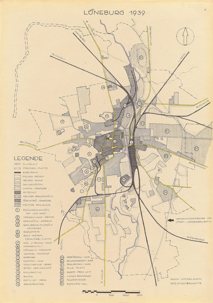 Es ist ein vergilbter Bebauungsplan der Stadt Lüneburg in schwarz-weiß mit gelb hervorgehobenen Hauptverkehrsachsen und blau hervorgehobenem Flusslauf der Ilmenau. Verschiedene Gebiete sind unterschiedlich schraffiert. Eine unten links platzierte Legende gibt Aufschluss darüber, welche Gebiete landwirtschaftlich, industriell, oder militärisch genutzt werden, und wo sich Wiesen, Felder und Wohngebiete befinden. 26 Anlagen sind mit Nummern gekennzeichnet und ebenfalls in der Legende aufgeführt. Hierzu gehören das Krankenhaus, Friedhöfe, aber auch die Kasernen, das Elektrizitätswerk und andere Infrastrukturen der Stadt Lüneburg.