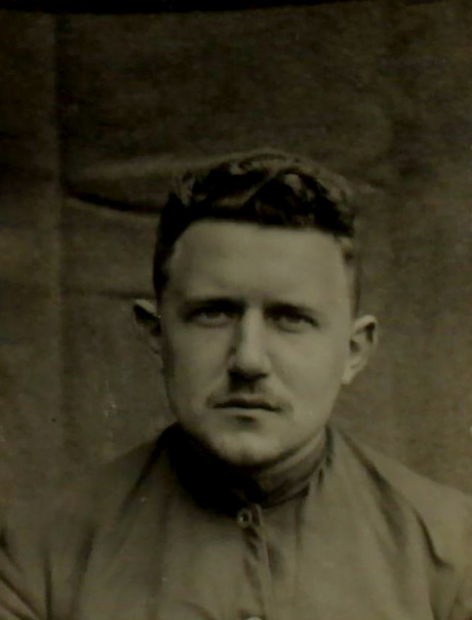 Es ist ein Schwarz-Weiß-Porträt. Heinrich Biester blickt mit geschlossenem Mund in die Kamera. Er trägt ein dunkles hochgeschlossenes Hemd. Das Foto ist zweimal gelocht und an den Kanten leicht abgewetzt.