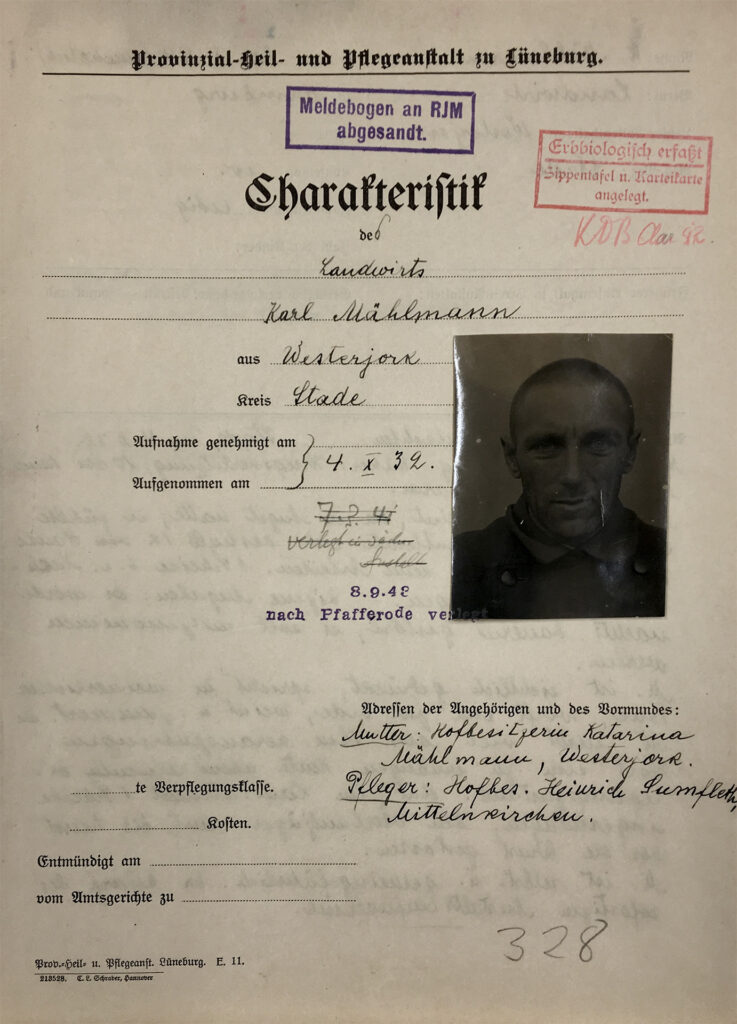 Das Dokument ist vergilbt. Die gedruckten Kategorien wurden mit der Hand ausgefüllt. Die Schrift auf der Rückseite drückt deutlich durch. Es ist ein Porträtfoto mit Karl Mählmann aufgeklebt. Der Bogen trägt einen roten Stempel: Erbbiologisch erfasst. Ein zweiter Stempel lautet: Meldebogen an RJM abgesandt.