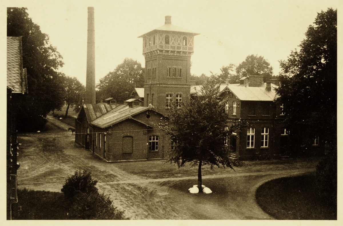 Der Wasserturm ist aus Backstein und oben mit Fachwerk gestaltet. Er hat vier Etagen. Er ist viereckig und hat ein flaches Walmdach. Darum herum stehen andere Backsteingebäude. Der Turm überragt die umgebenden Gebäude. Vor dem Turm steht ein einzelner Baum.