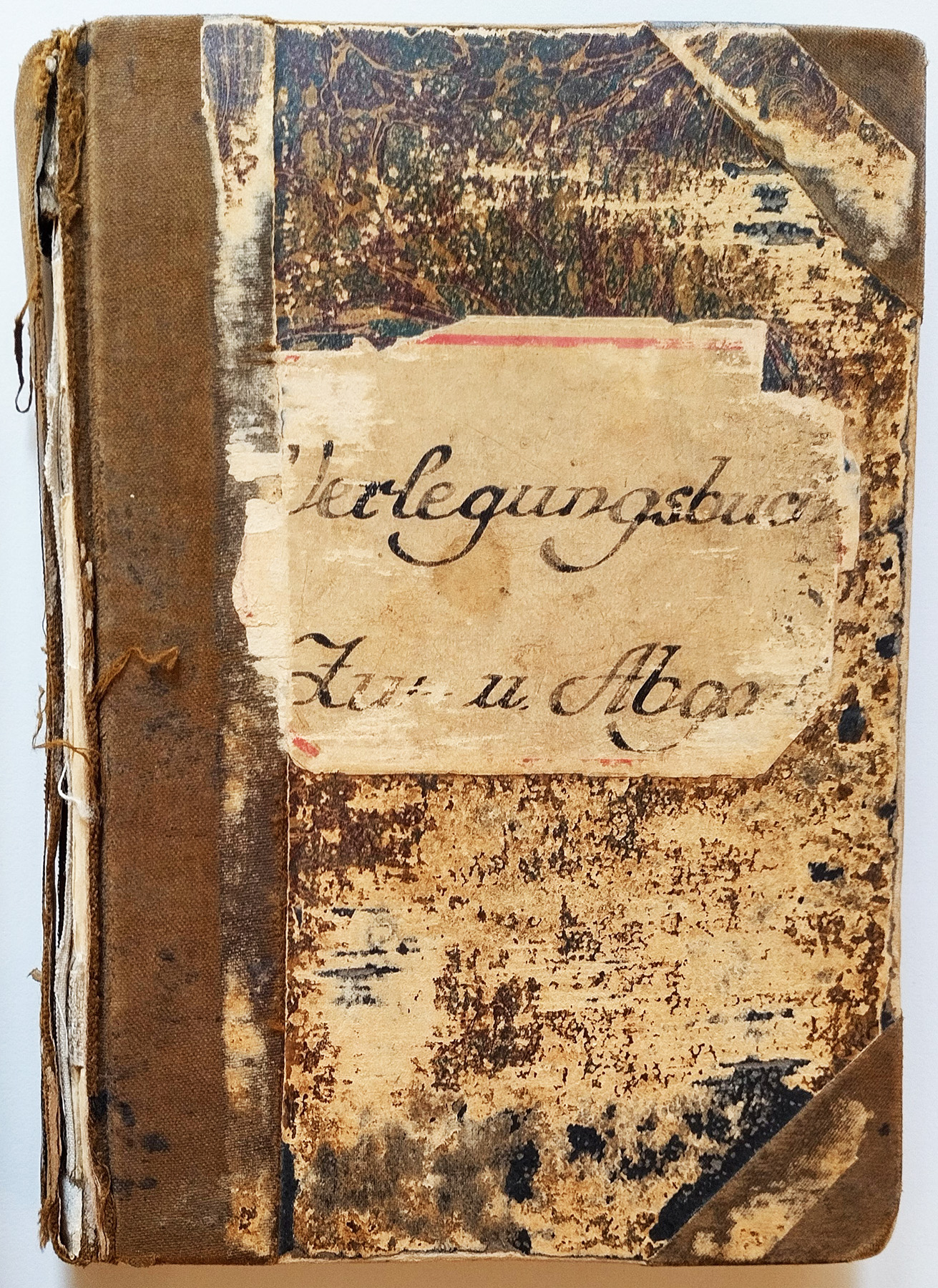 Das Verlegungsbuch ist in Leinen gebunden und hat ein helles Schild mit dem Titel. Das Buch ist von außen stark abgenutzt. Der Titel ist teilweise nicht mehr lesbar.