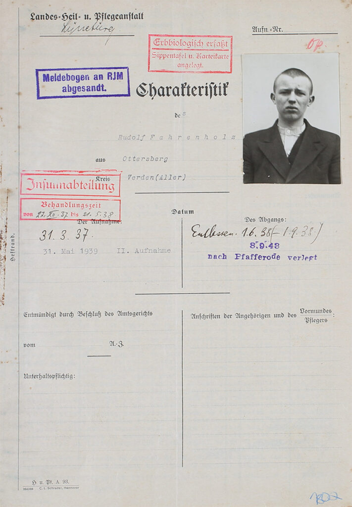 Das Dokument ist vergilbt. Die gedruckten Kategorien wurden mit der Hand ausgefüllt. Die Schrift auf der Rückseite drückt deutlich durch. Auf dem Dokument ist ein Porträtfoto von Rudolf Fahrenholz aufgeklebt. Der Bogen trägt einen roten Stempel: Erbbiologisch erfasst. Ein zweiter Stempel lautet: Meldebogen an RJM abgesandt. Ein dritter Stempel verweist darauf, dass er in der Insulinabteilung behandelt wurde in der Zeit vom 27. Dezember 1937 bis 21. Mai 1938. Auf dem Foto hat Rudolf Fahrenholz kurz geschorene Haare. Er trägt ein krangenloses Hemd mit einer dunklen Weste und einem dunklen Jackett. Seine Stirn ist kraus und er schaut hilflos in die Kamera. Über seinem Foto ist mit rotem Buntstift »OP« vermerkt.