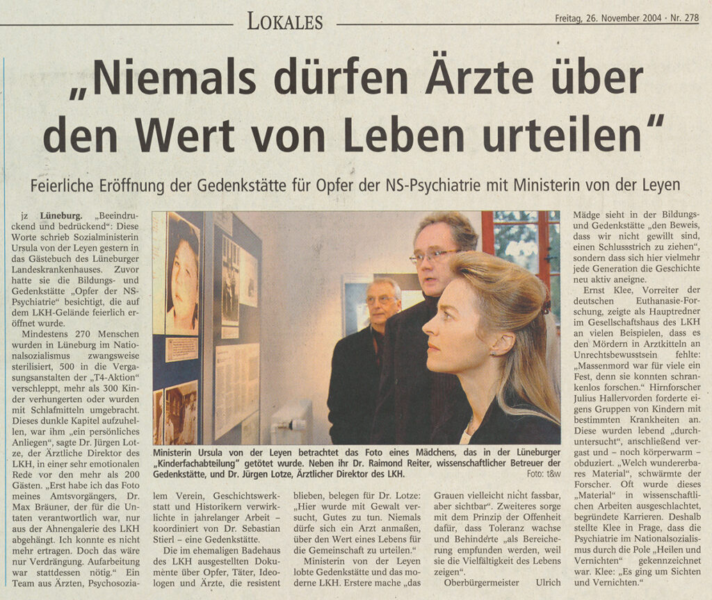 Es ist ein Foto eines Zeitungsartikels. Mittig im Text unter der Überschrift ist ein großes farbiges Bild. Es zeigt eine Seitenaufnahme von Ursula von der Leyen vor einer Wand mit Bildern. Sie blickt ernst nach links. Im Hintergrund sind Dr. Raimond Reiter und Dr. Jürgen Lotze zu sehen, die ihr zugewandt stehen.