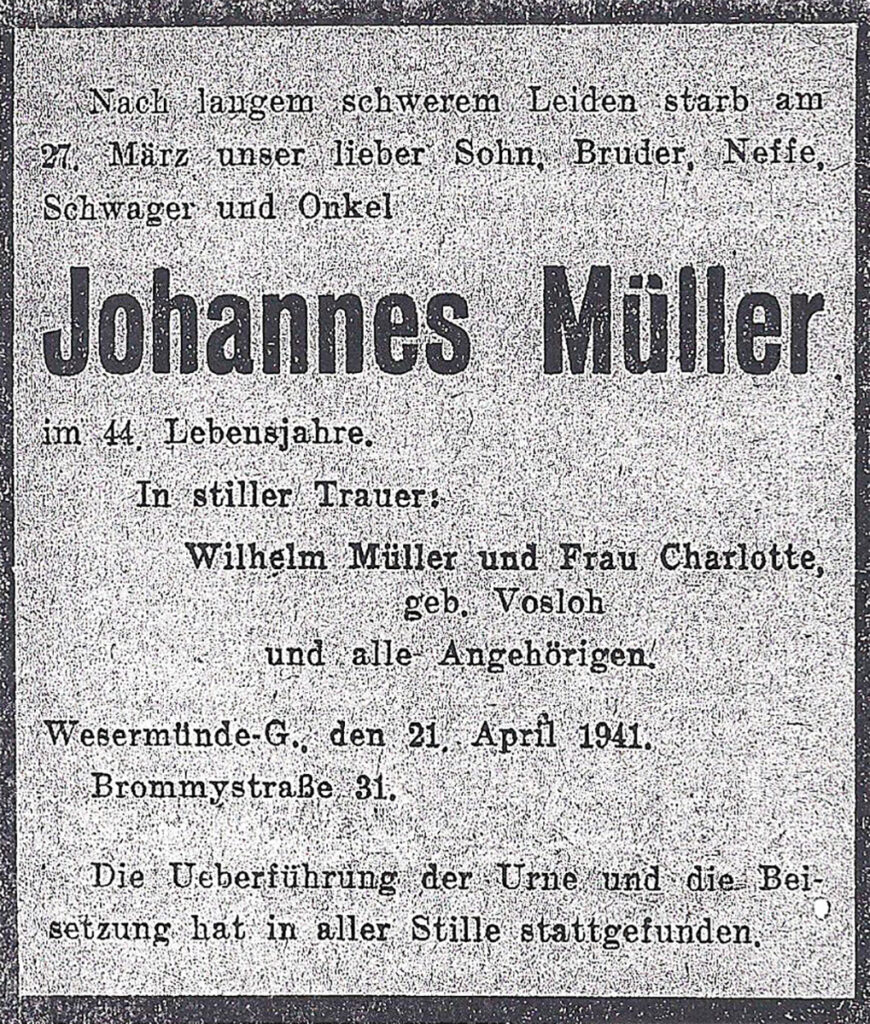 Es ist eine schwarz-weiße, grobe Kopie einer Todesanzeige aus der Zeitung. Sie ist umrandet mit einem dicken schwarzen Rand. Johannes Müller wird von seinen Eltern im Namen seiner Familie gedacht.
