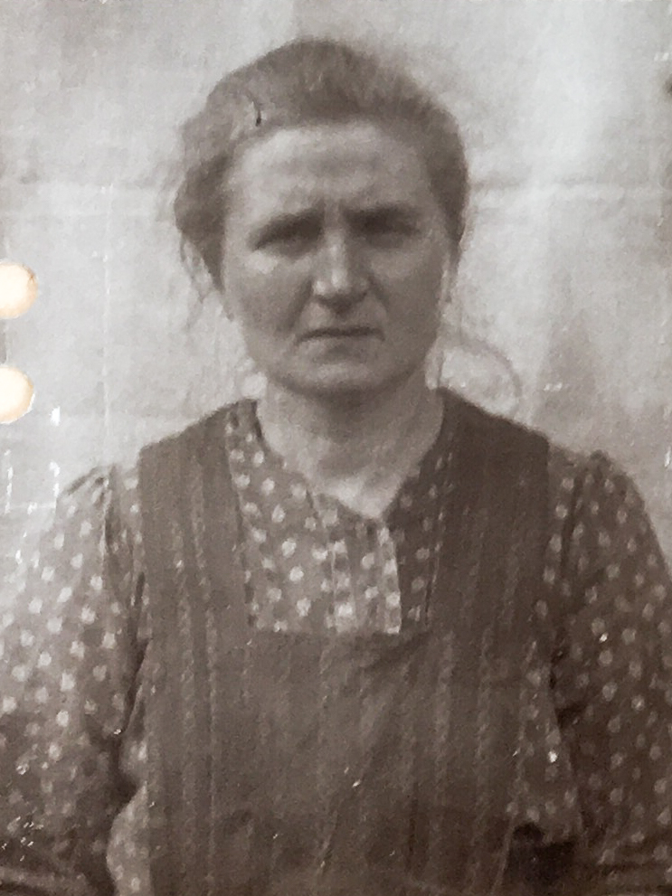 Es ist ein schwarz-weißes Porträtfoto. Es ist sehr dunkel. Ida Dittrich trägt die Haare locker nach hinten gebunden. Sie trägt eine geblümte Bluse und darüber ein dunkles Trägerkleid oder Hemd. Sie blickt ernst in die Kamera.