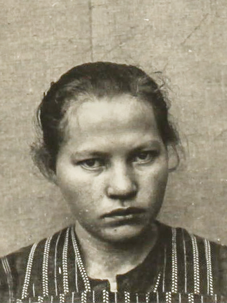 Es ist ein schwarz-weißes Porträtfoto. Frida Timme trägt die Haare locker zurückgebunden. Sie hat ein karierte Bluse an. Sie hält den Kopf leicht zur Seite und guckt in die Kamera. Ihr Blick wirkt skeptisch.