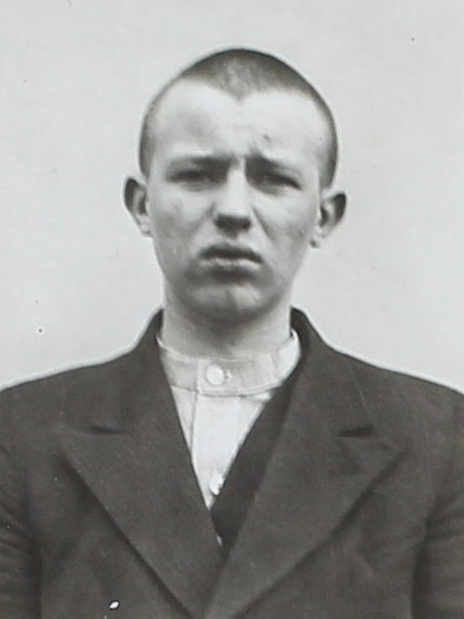 Es ist ein schwarz-weißes Porträtfoto. Es ist sehr hell. Rudolf Fahrenholz trägt eine dunkle geknöpfte Jacke. Sein Haar ist kurz geschoren. Er guckt mit ernstem Blick in die Kamera.