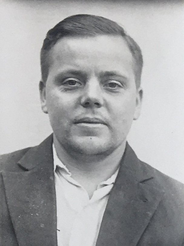 Es ist ein schwarz-weißes Porträtfoto. Adolf Bremer trägt eine dunkle Jacke zu einem hellen Hemd. Sein Haar ist nach hinten gekämmt. Er guckt in die Kamera.