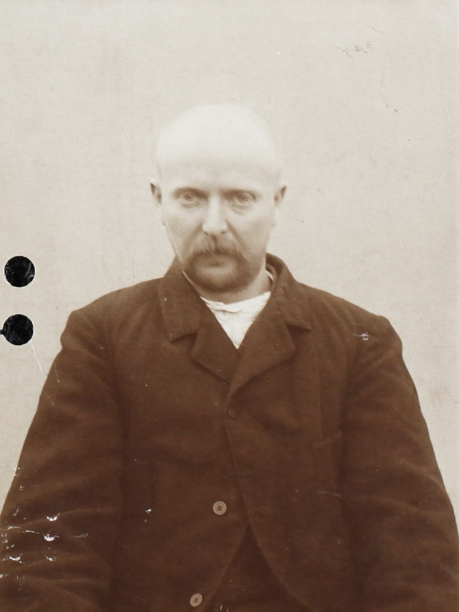 Es ist ein schwarz-weißes Porträtfoto. Arnold Böther trägt eine dunkle schwere Jacke. Sein Haar ist kurz geschoren. Er trägt einen Schnauzbart. Er guckt ernst in die Kamera.