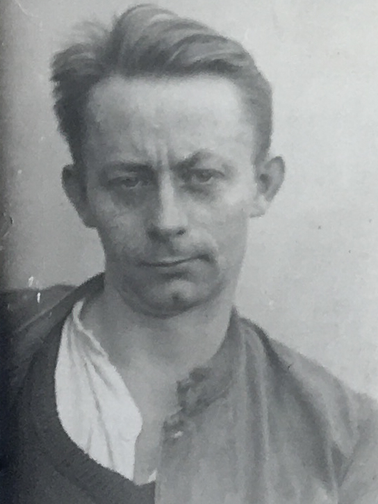Es ist ein schwarz-weißes Porträtfoto. Friedrich Peters trägt ein helles Hemd mit offener Jacke darüber. Sein Haar ist nach oben gekämmt. Er guckt mit zusammengezogenen Augenbrauen in die Kamera.