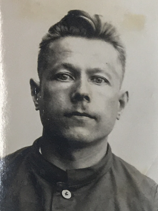 Es ist ein schwarz-weißes Porträtfoto. Heinrich Tiedemann trägt ein dunkles Hemd. Sein Haar ist nach oben gekämmt. Er guckt in die Kamera.