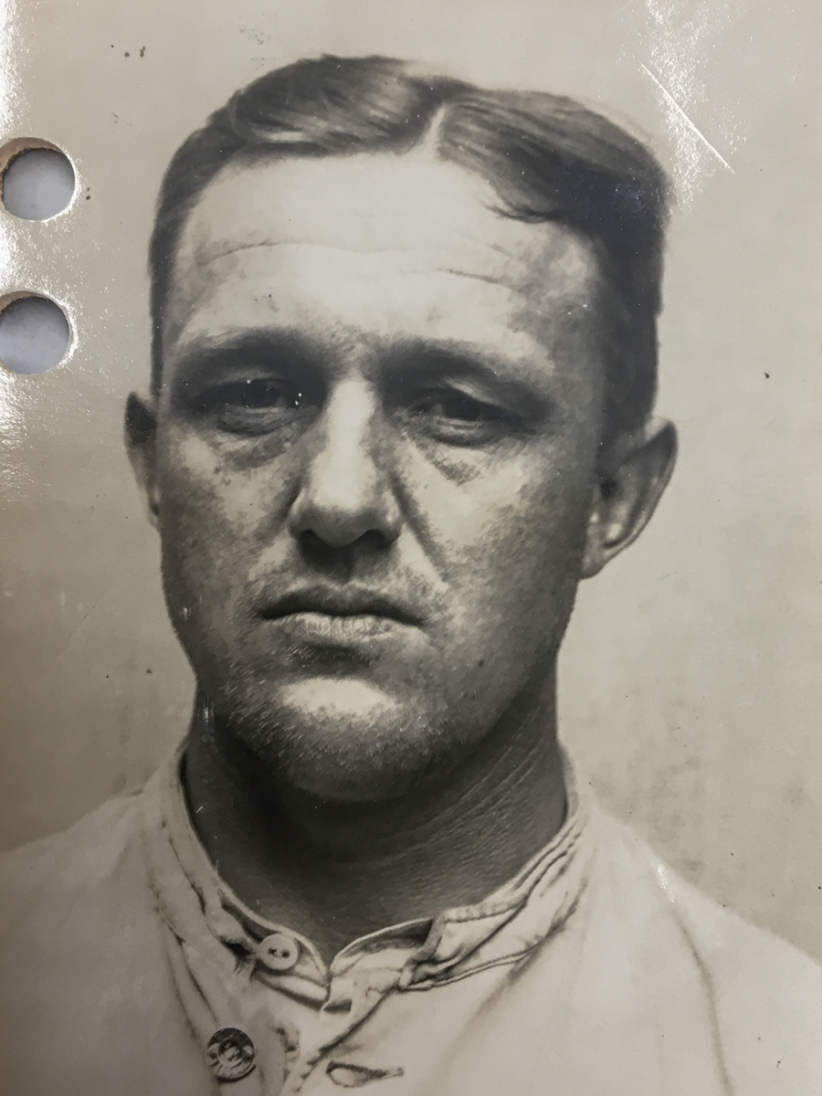 Es ist ein schwarz-weißes Porträtfoto. Adolf Veersmann trägt ein helles Hemd. Sein Haar ist zu den Seiten gekämmt. Er guckt ernst in die Kamera.