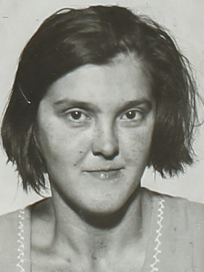 Es ist ein schwarz-weißes Porträtfoto. Gertrud Glass trägt eine helle Bluse. Die kinnlangen Haare sind offen. Sie blickt leicht lächelnd in die Kamera.