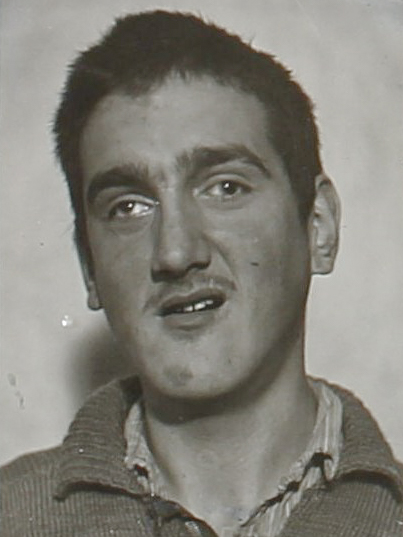 Es ist ein schwarz-weißes Porträtfoto. Herbert Glass trägt ein dunkles Hemd. Die Haare sind kurz geschnitten. Sie wirken strubbelig. Er trägt einen kurzen Bart und blickt in die Kamera.